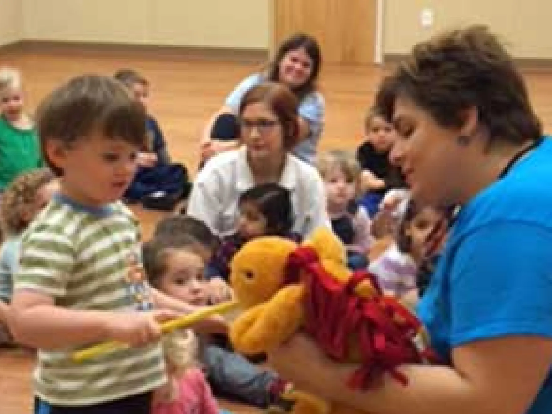 Children interact with a puppet during a dental education event in a community room.