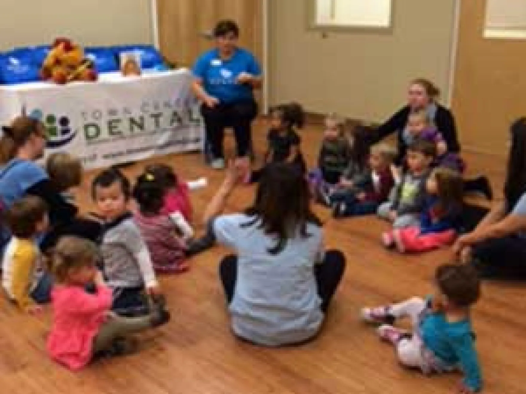 Town Center Dental staff conducting children's dental health education event with young kids in community room.