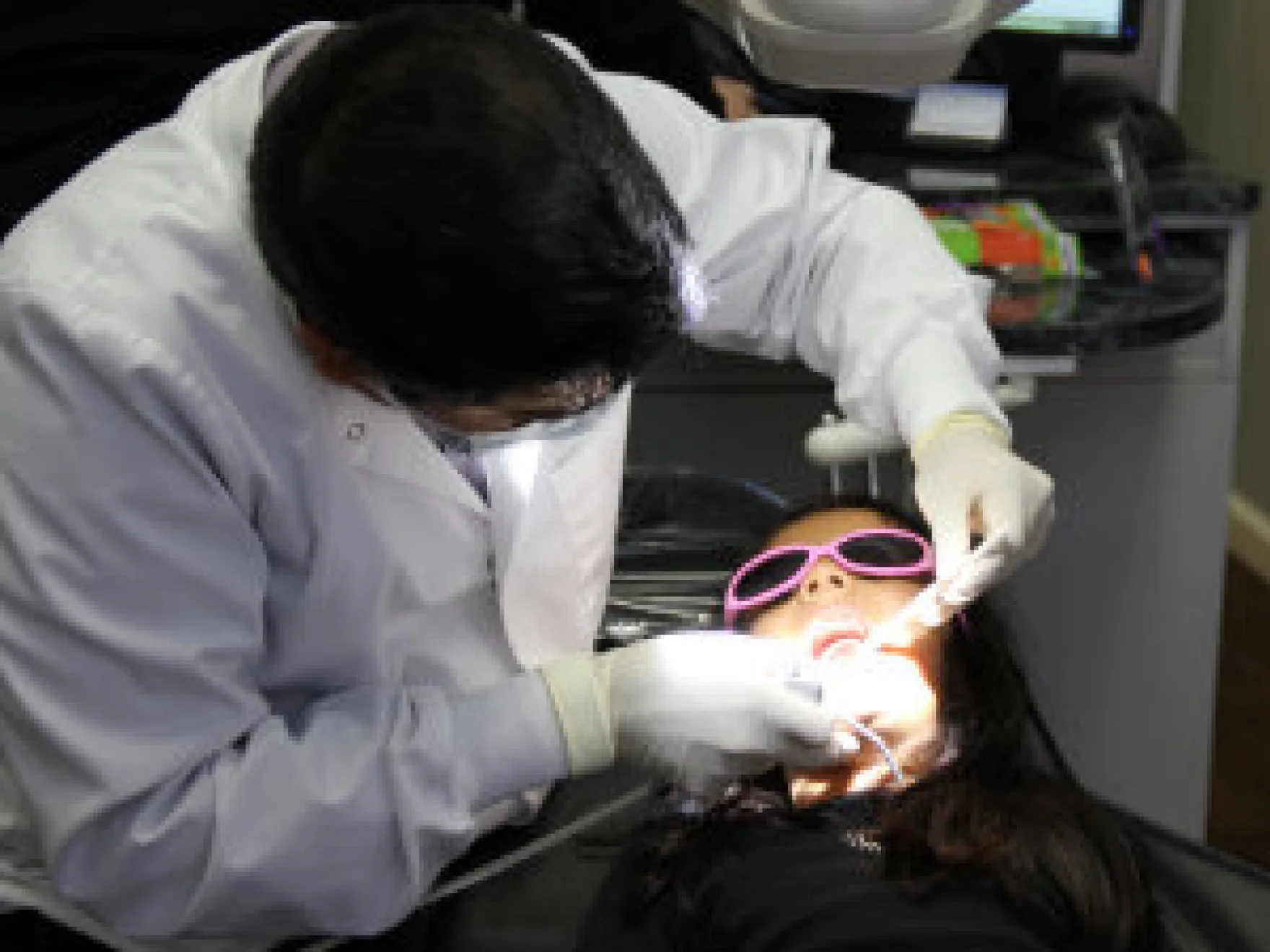 Dental professional examining patient's teeth wearing protective gloves in clinical setting.