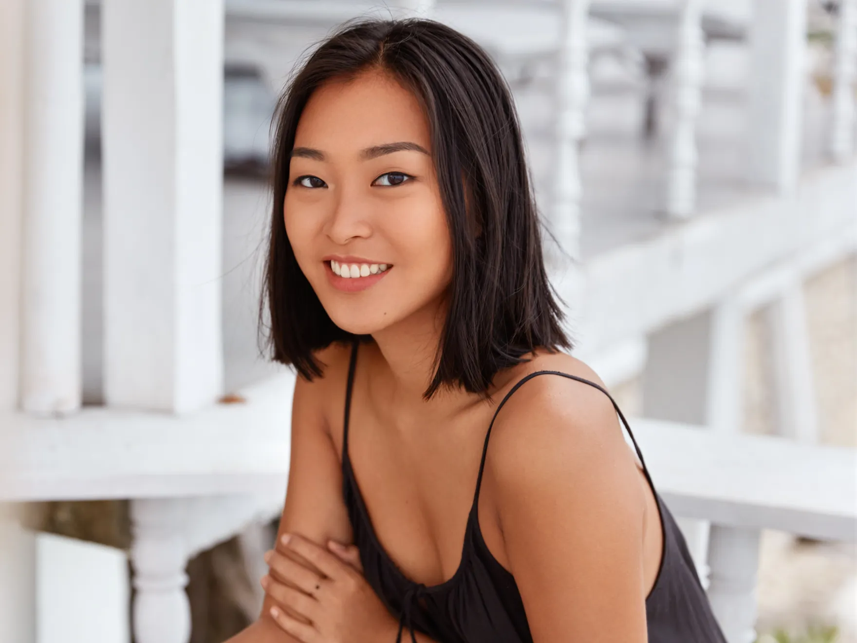 Woman smiling at camera in bright, modern dental office setting with white background.