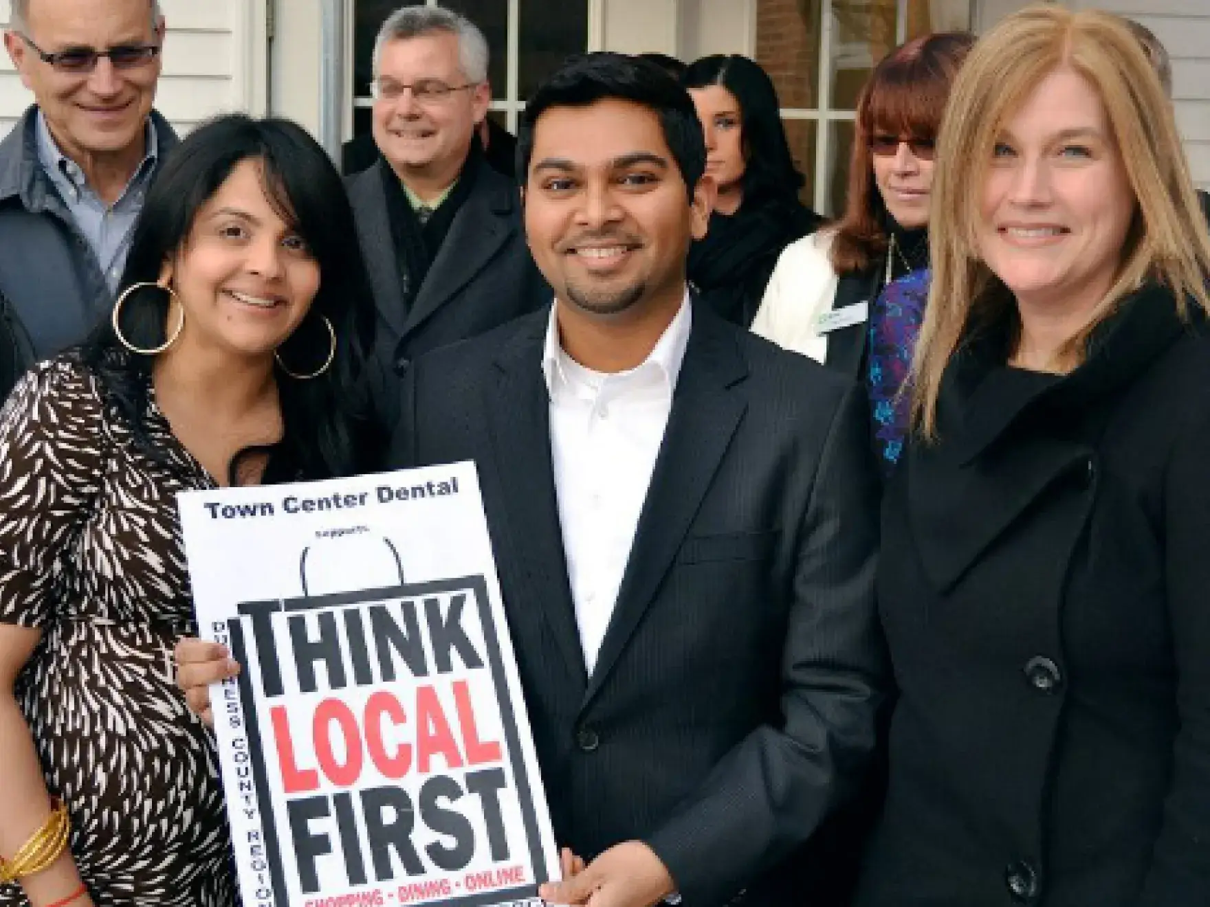 Group of professionals holding "Think Local First" sign for Town Center Dental LaGrange promotion.