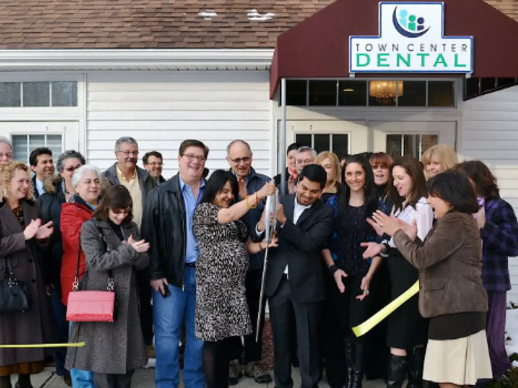 Large group of people at ribbon cutting ceremony outside Town Center Dental storefront.