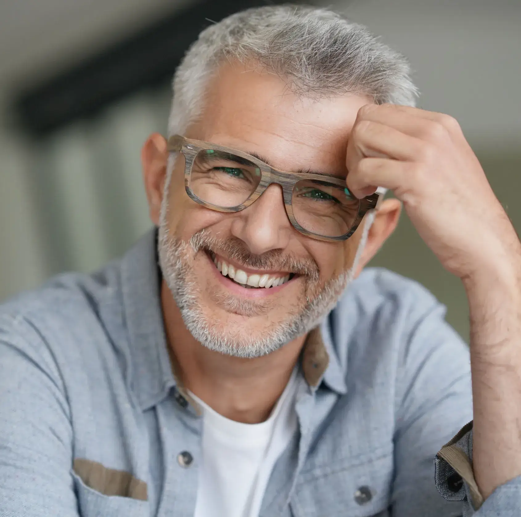 Smiling middle-aged man wearing glasses and light blue shirt in professional portrait setting.