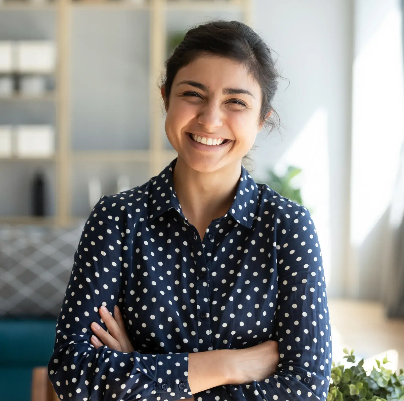 Smiling woman in navy polka dot shirt in modern dental office interior with plants.