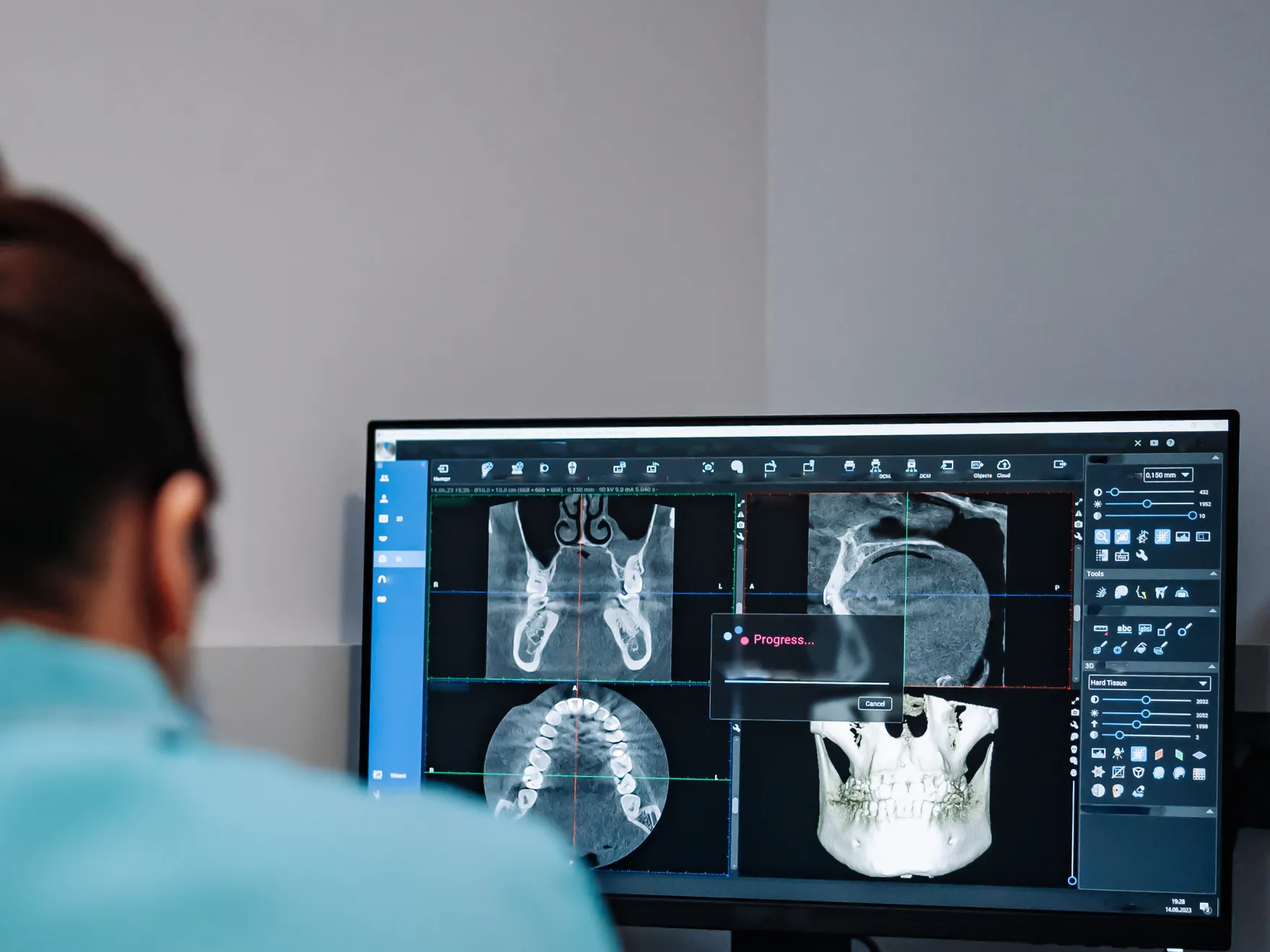 Dentist reviews dental imaging software displaying multiple X-ray and scan images on computer monitor.
