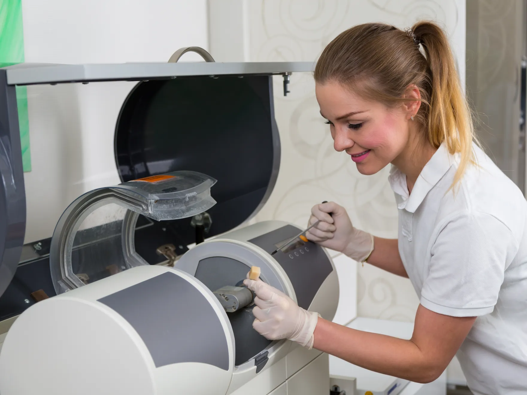 Dental technician operating laboratory equipment in professional dental office setting.