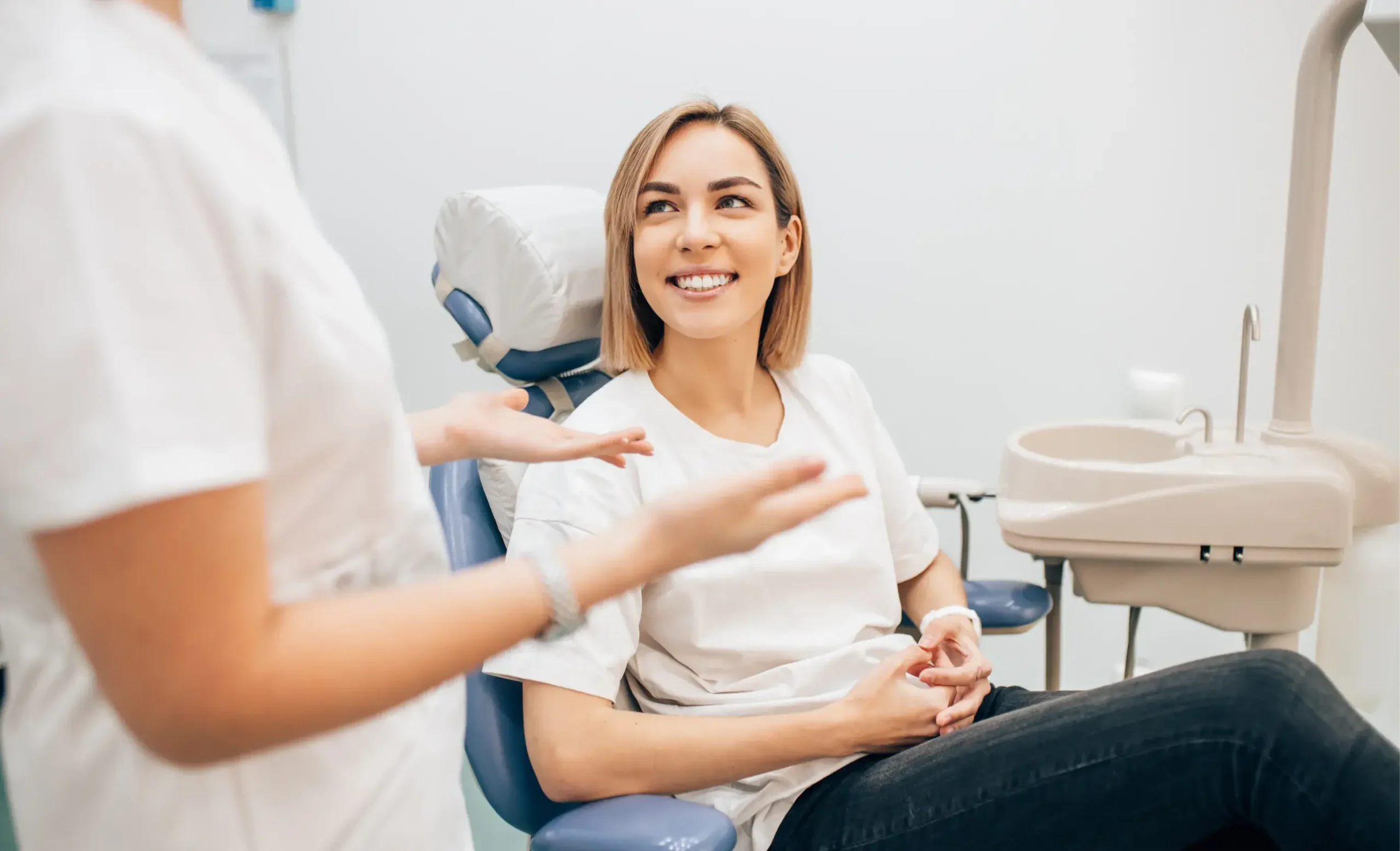 Smiling patient in dental chair receiving consultation from dentist in modern dental office.