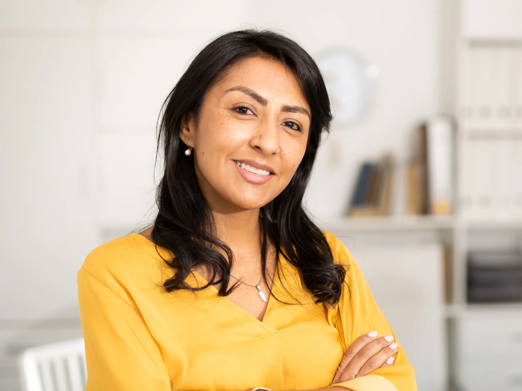 Professional woman in yellow top smiling at dental office reception area.