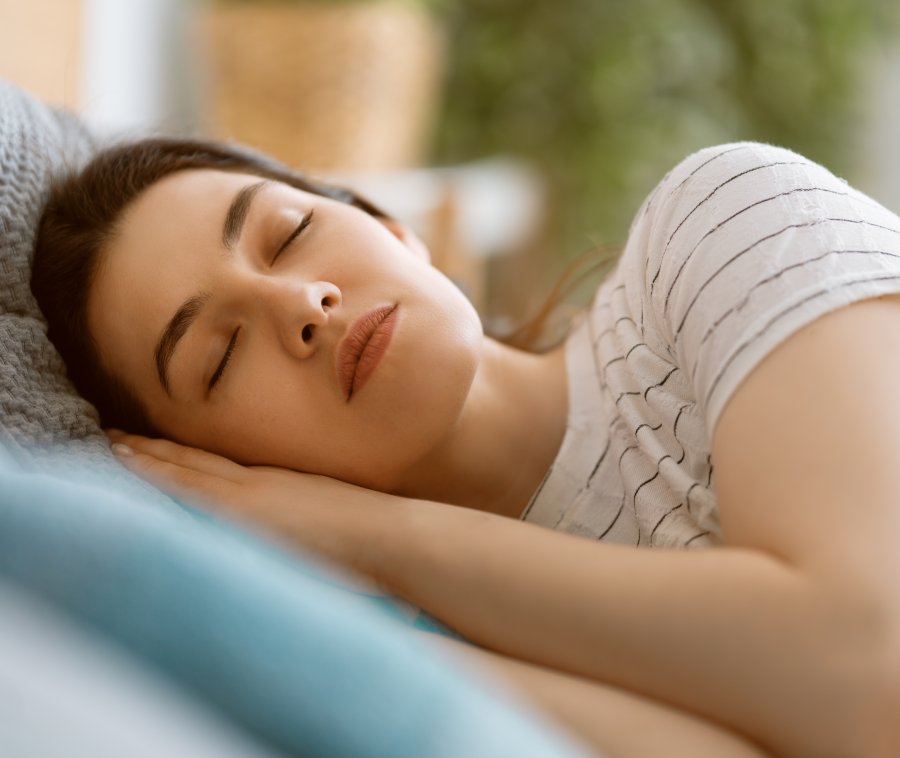 Woman sleeping peacefully on pillow with eyes closed in relaxed indoor setting.