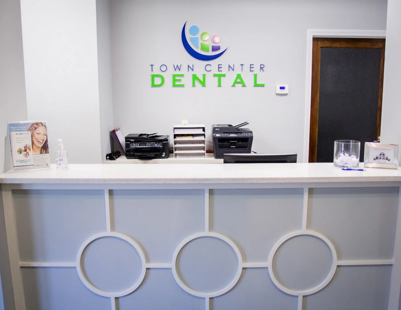 Town Center Dental reception desk with logo, office equipment, and waiting area seating.
