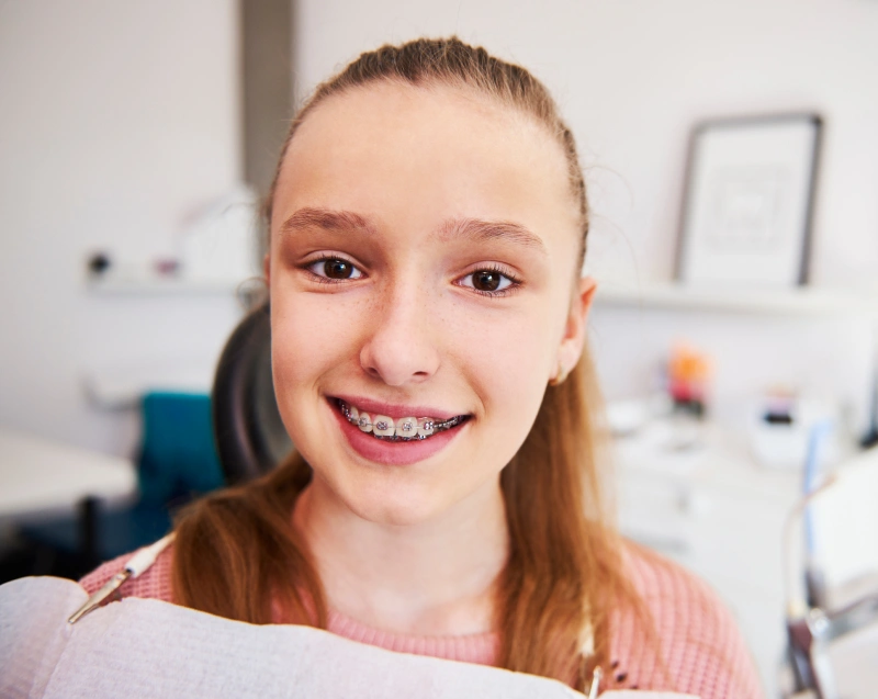 Young girl with braces smiling in dental office treatment room