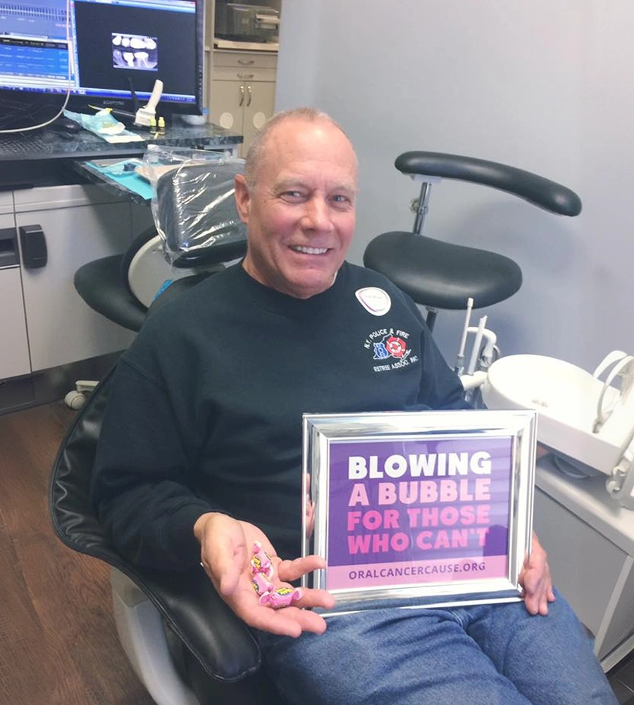 Man holding framed oral cancer awareness sign in dental office treatment room
