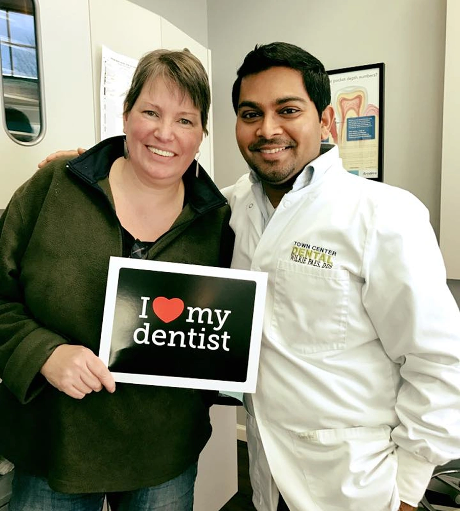 Patient and dentist holding "I love my dentist" sign in dental office at Town Center Dental.