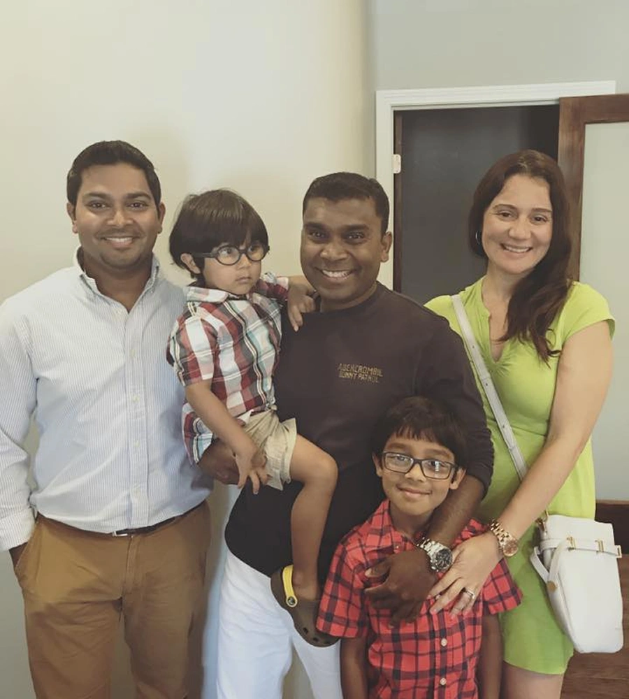Five people smiling together in a dental office interior setting for a family portrait.